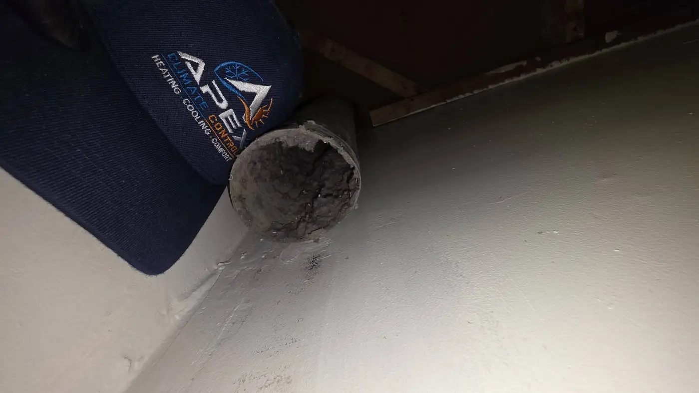 Dryer vent transition duct packed solid with lint next to an Apex Climate Control hat