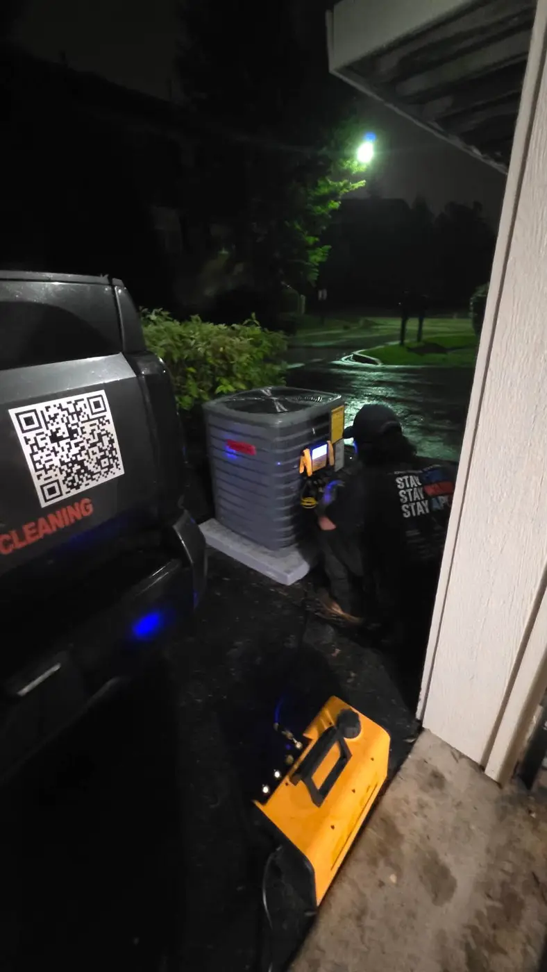 Apex Climate Control technician charging a new AC system at night in the rain